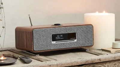 Ruark R3 kompaktes Music System Walnuss auf rustikalem Sideboard neben Kerze und Pflanze